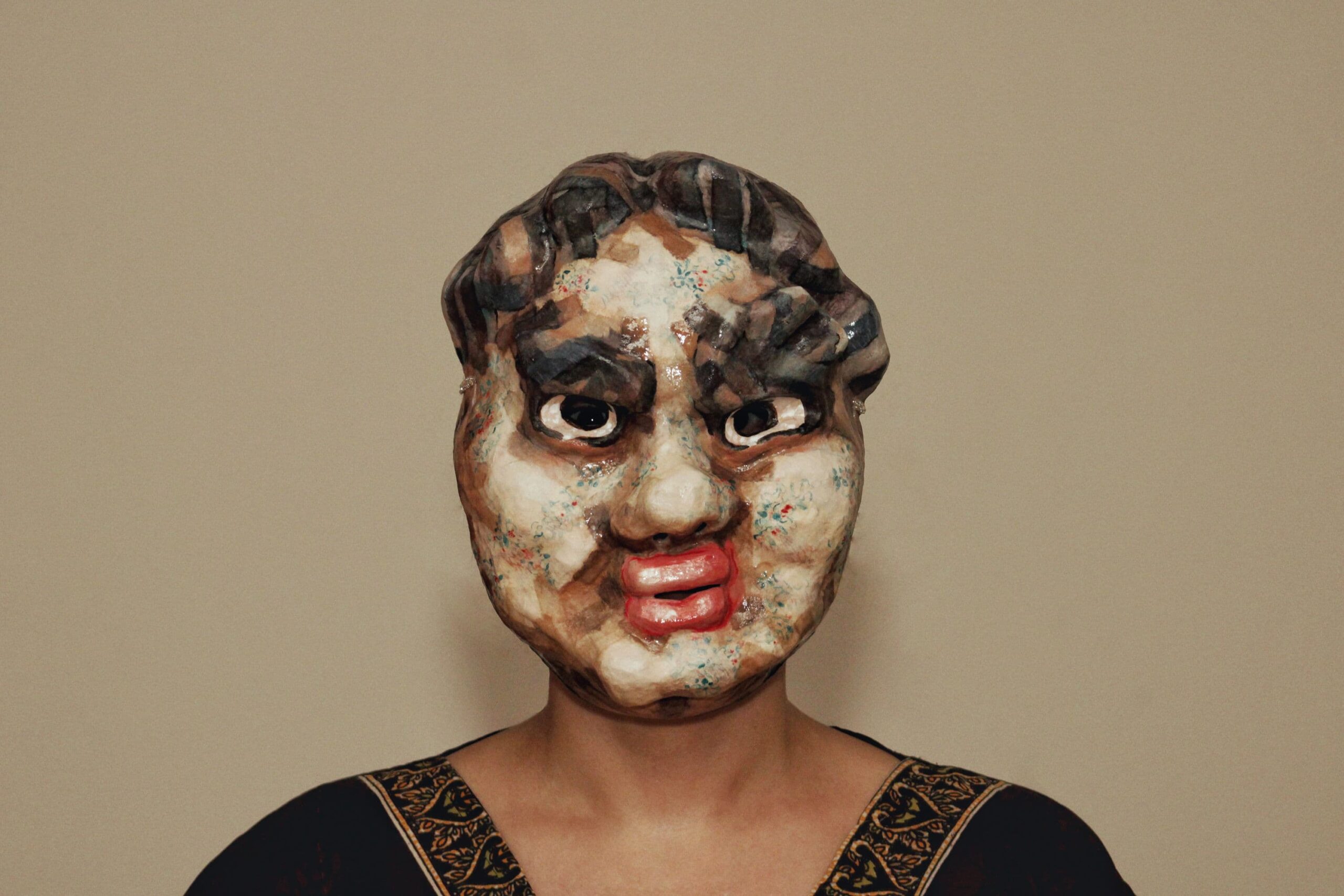 portrait of a lacquered mask evoking a fallen cartoon gangster - disdain etched in floral ink and bulging features