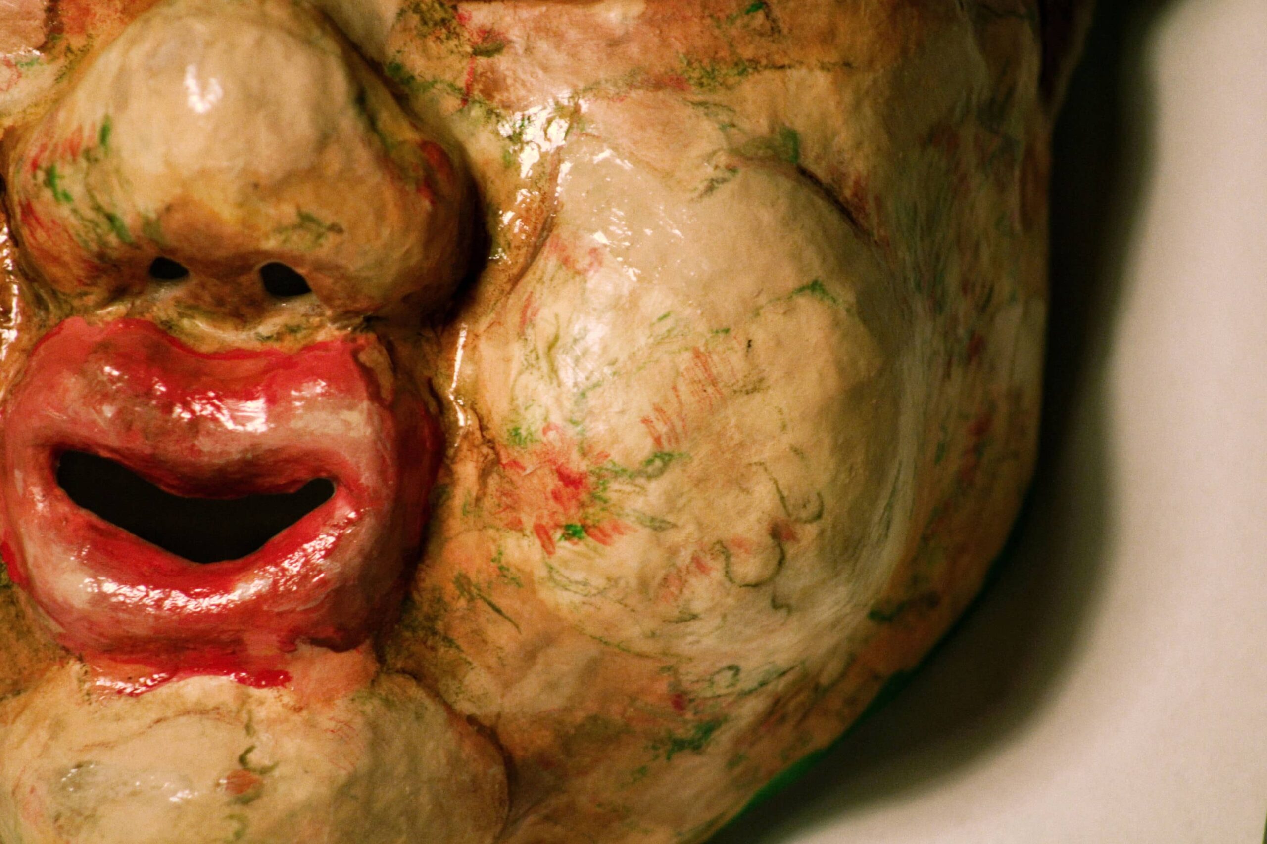 detail of a glossy sculpted cheek and open mouth, with gestural red and green linework