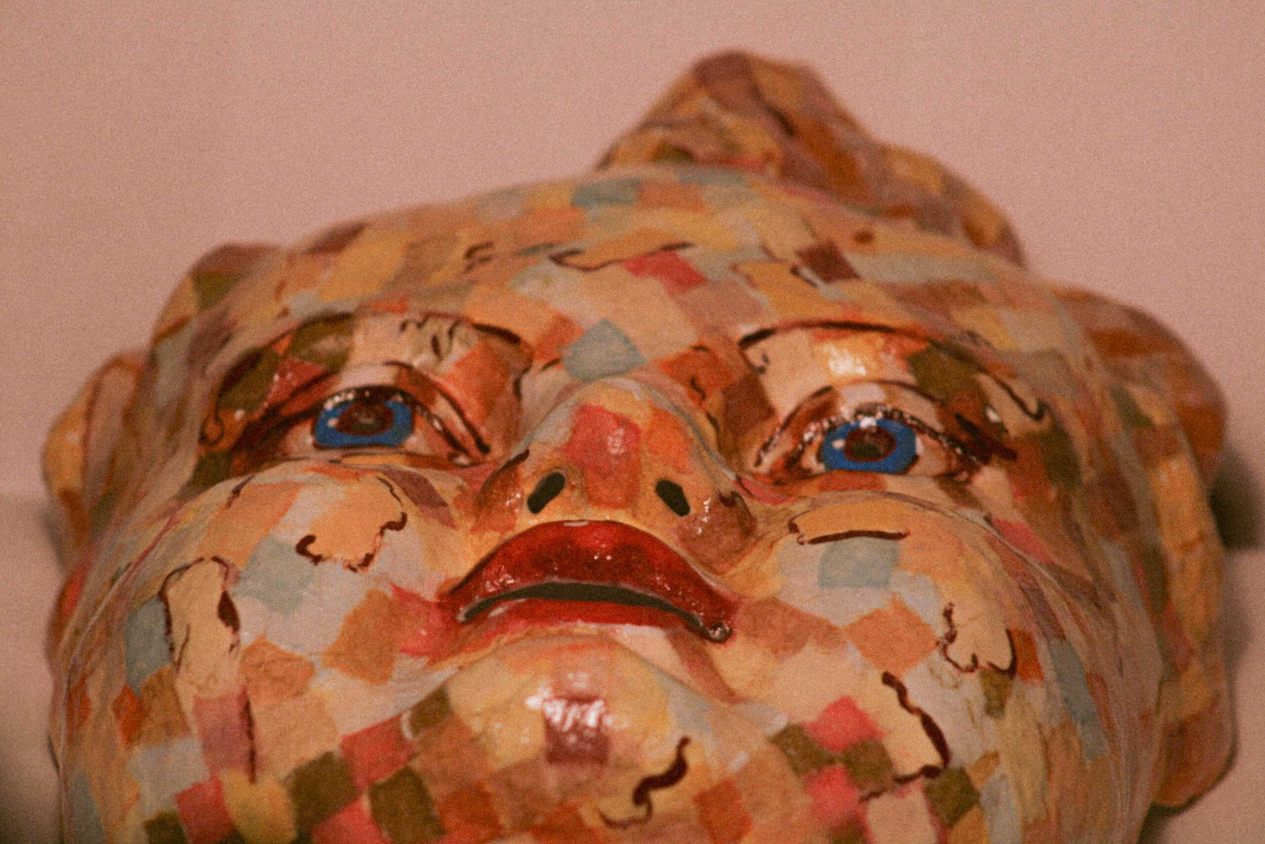 low-angle close-up of the face, focusing on the blue eyes, nose, and lips, with the patchwork pattern visible across the cheeks
