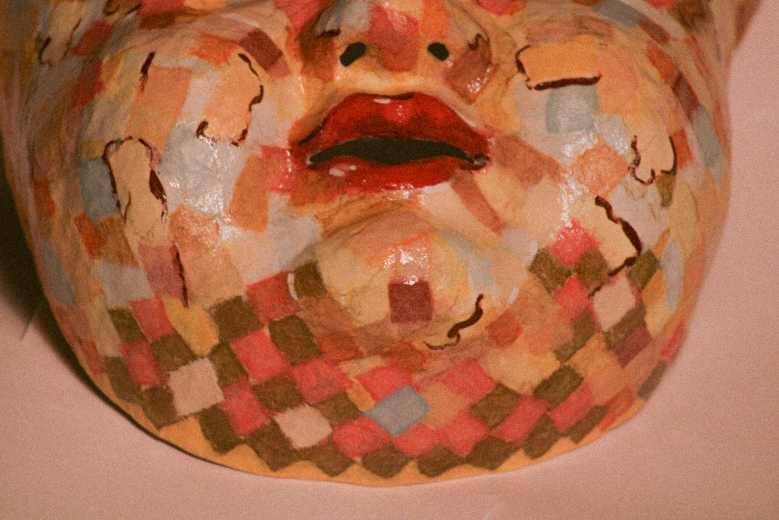close-up of the lower half of the sculpted face, focusing on the mouth and chin with red lips and tighly packed square color patches