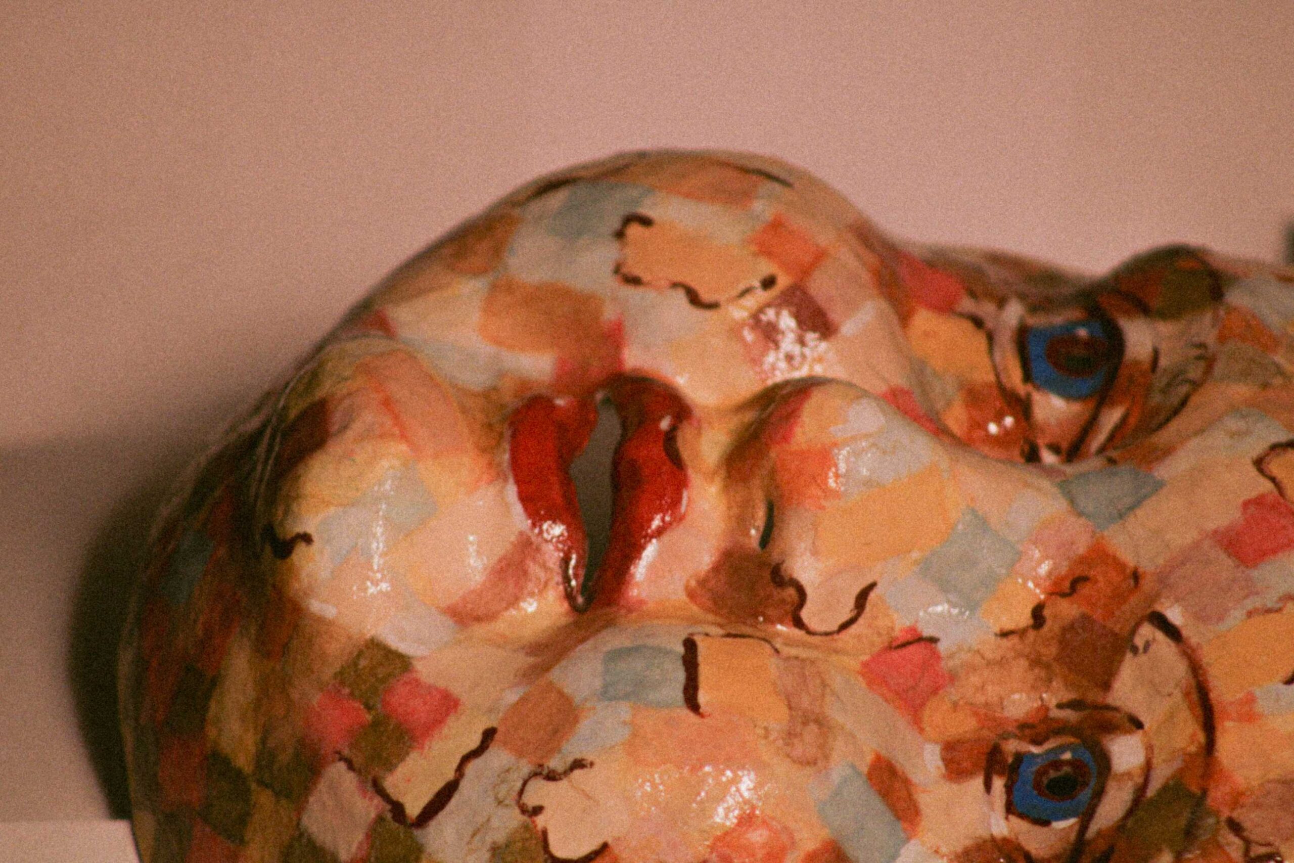 angled close-up of the face from below, emphasizing the nose and lips with glossy highlights and layered square paint patterns