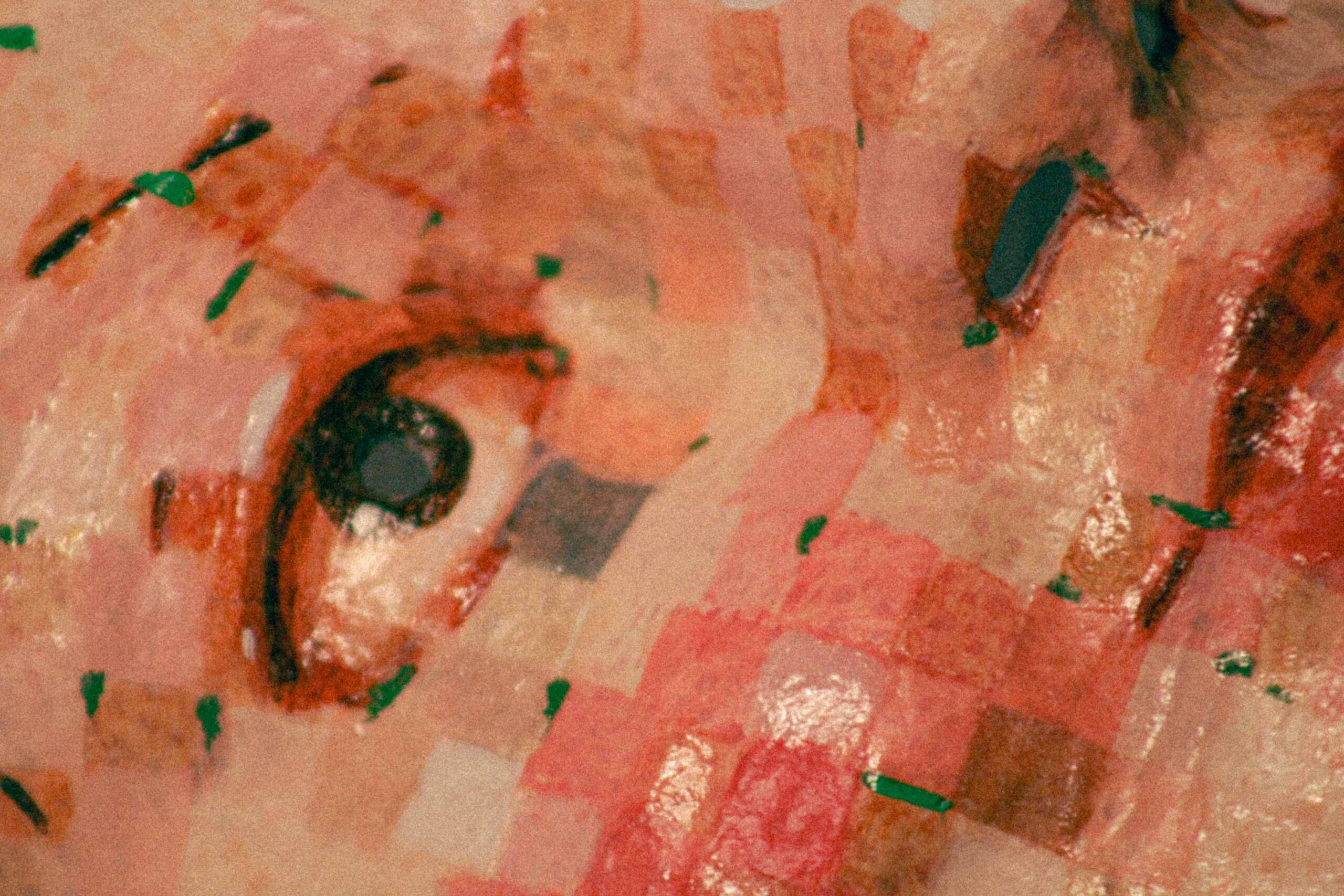 extreme close-up of one eye area of the mask, showing painted eyelashes, layered squares, and glossy texture