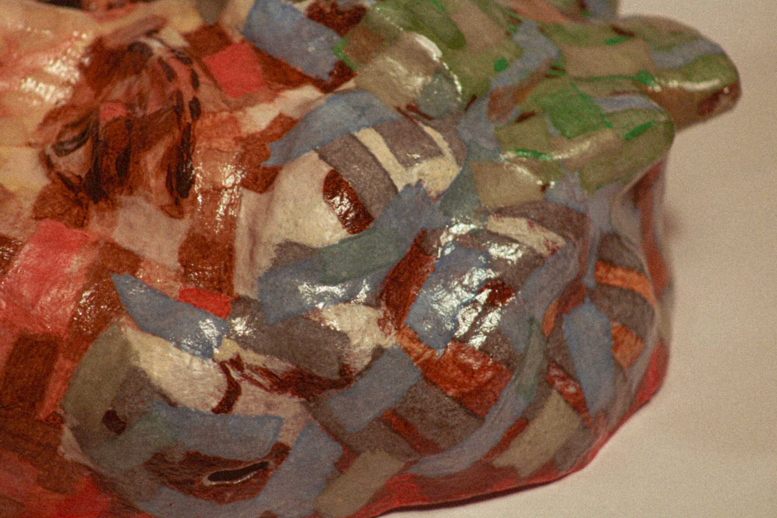 angled close-up of the side of the mask, showing overlapping blue, green, and brown paint fragments across the surface