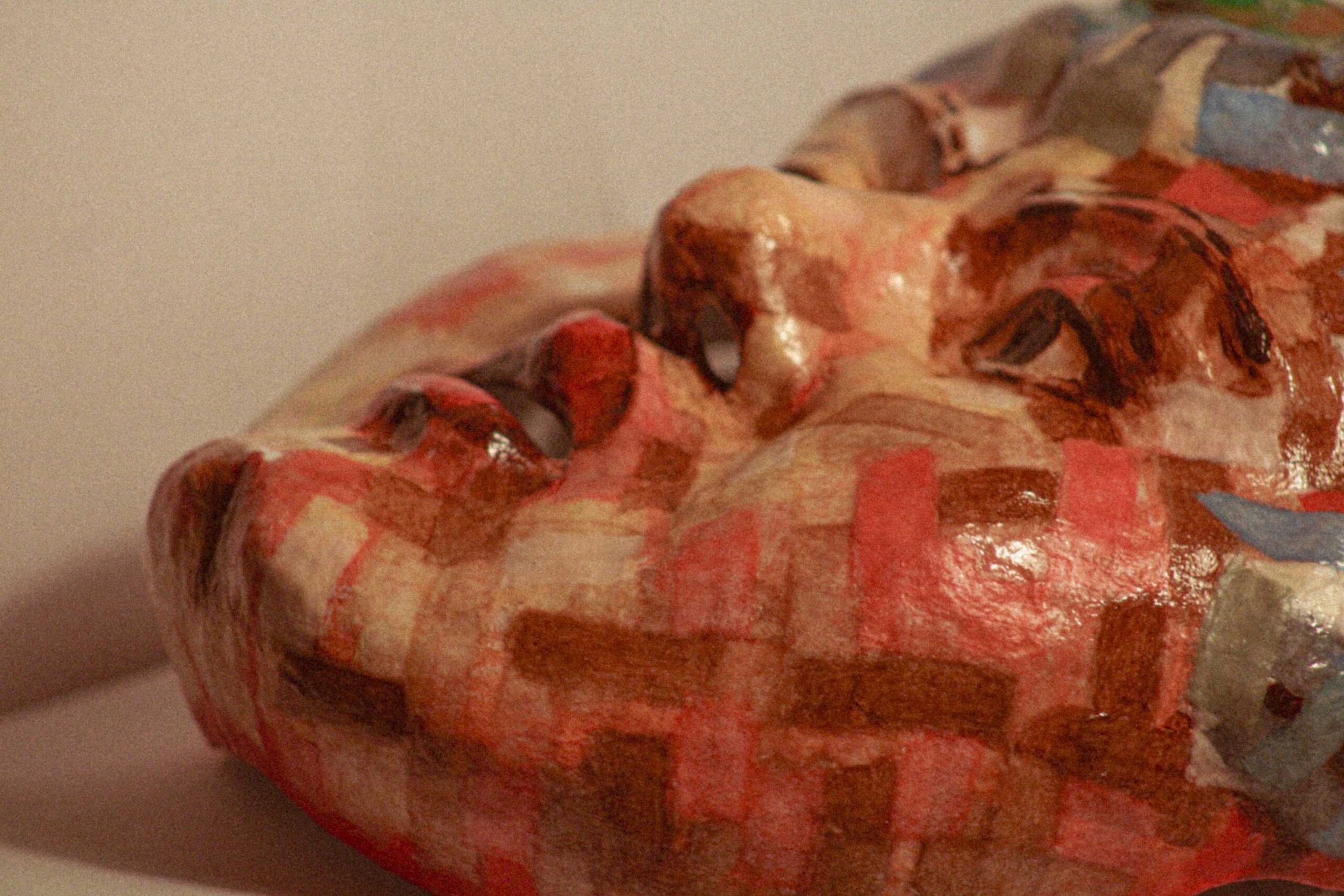 side profile of the sculpted face resting horizontally, emphasizing the nose, lips, and cheek with layered mosaic-like paint texture