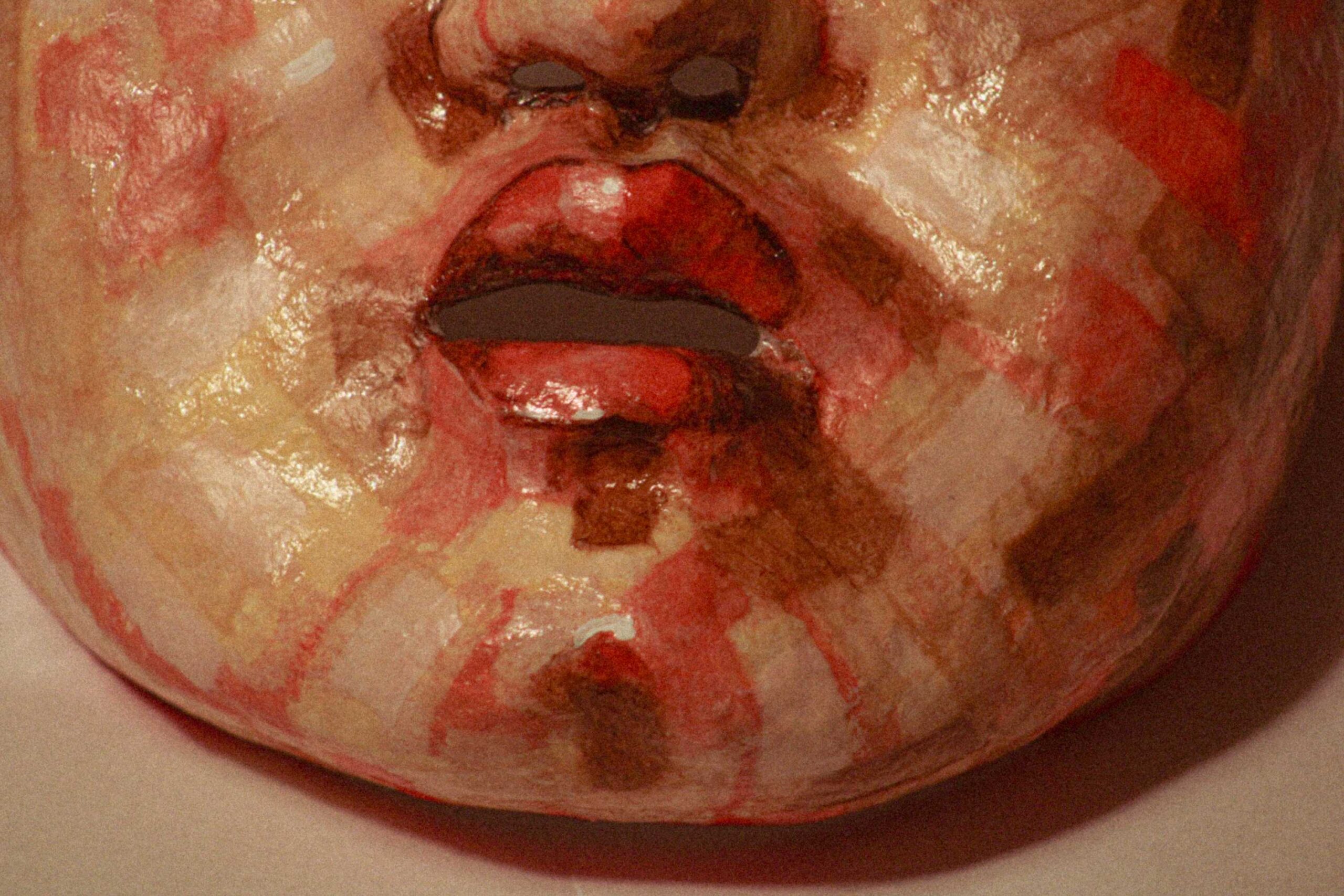 detail of the lower face of the sculpture, focusing on the mouth and chin with glossy, layered red and beige paint patches