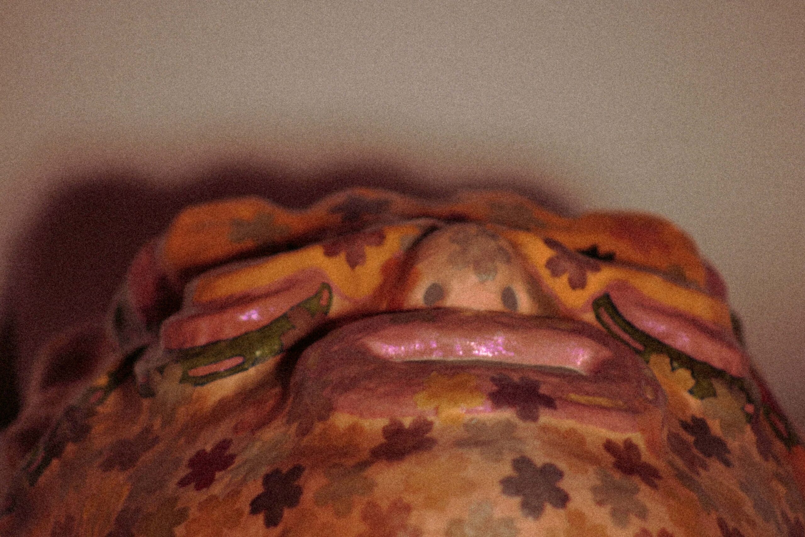 low-angle view of a sculptural art mask highlighting open mouth and exaggerated facial features