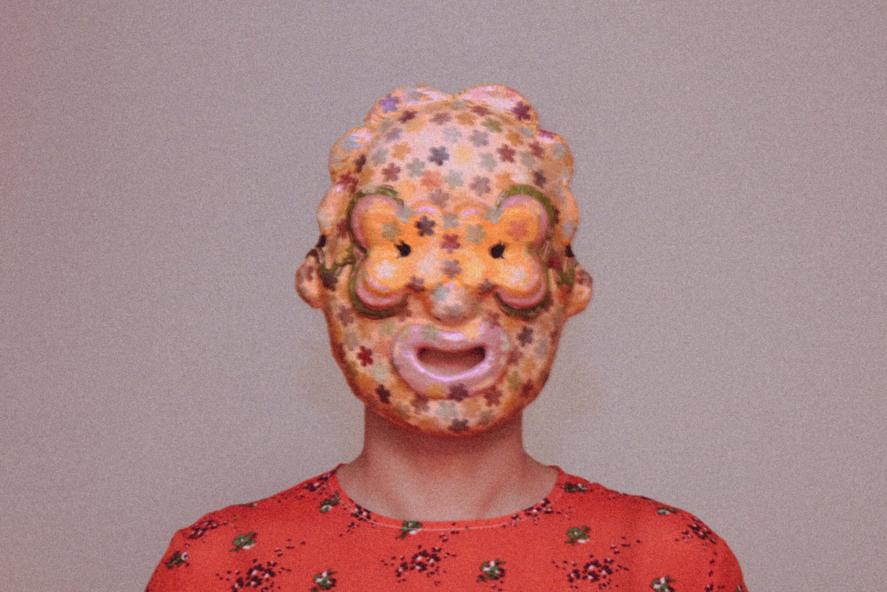 person wearing a handmade sculptural mask, showing fit on face and relationship between mask and body
