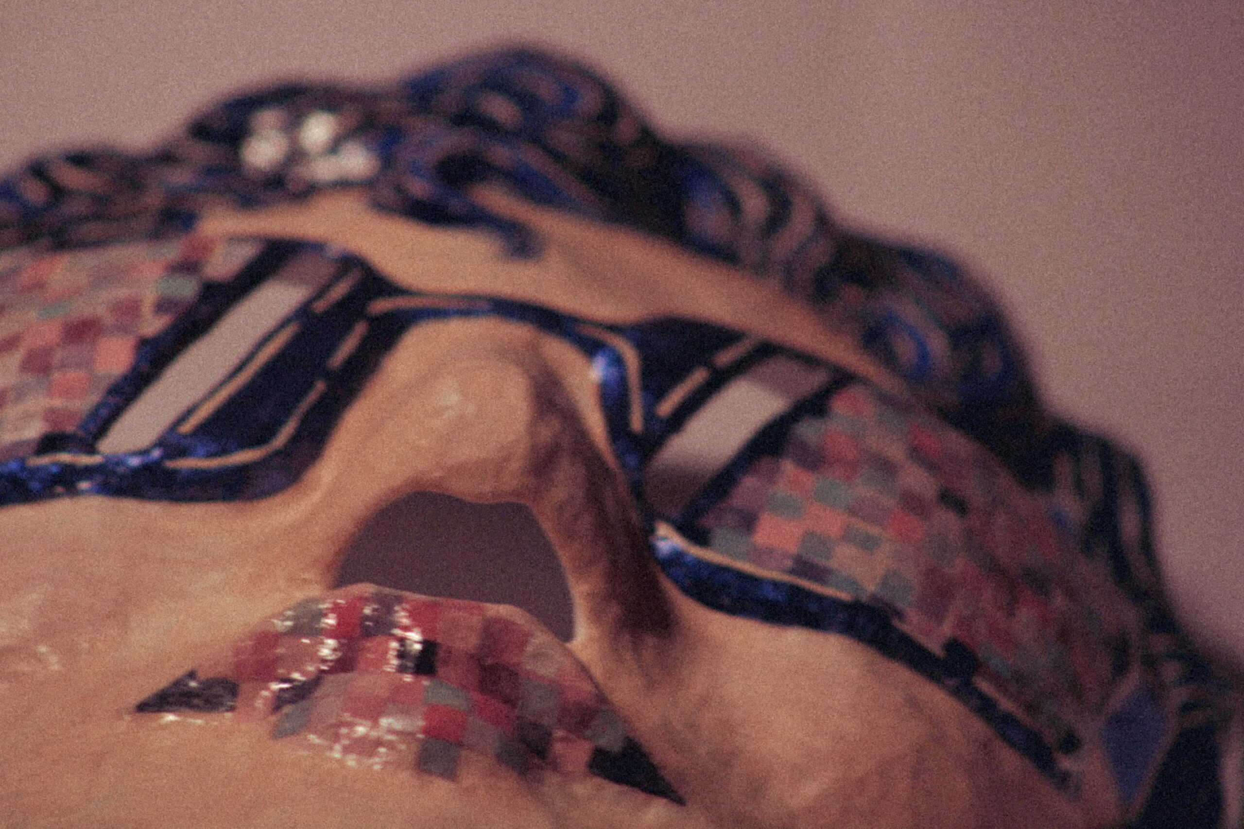 close-up low-angle view of a handmade mask showing nose, lips, and mosaic-like painted sunglasses