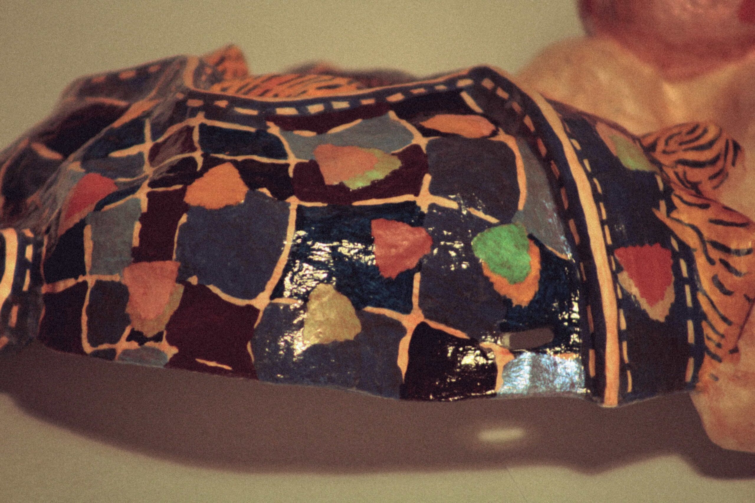 close-up side view of a handmade sculptural mask with mosaic-style painted surface and glossy finish