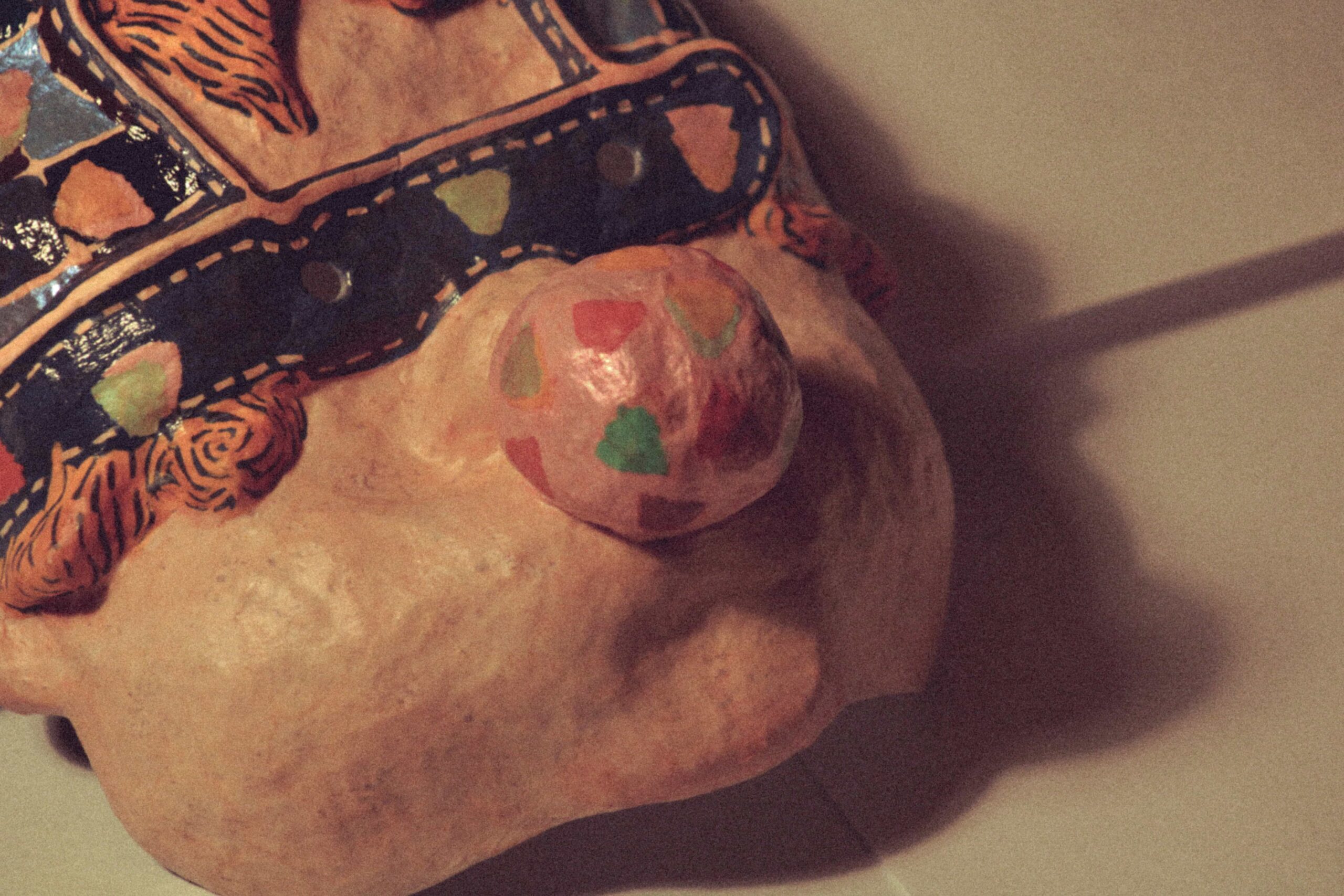 close-up of a handmade art mask showing a bubblegum balloon and a cap with textured painted details