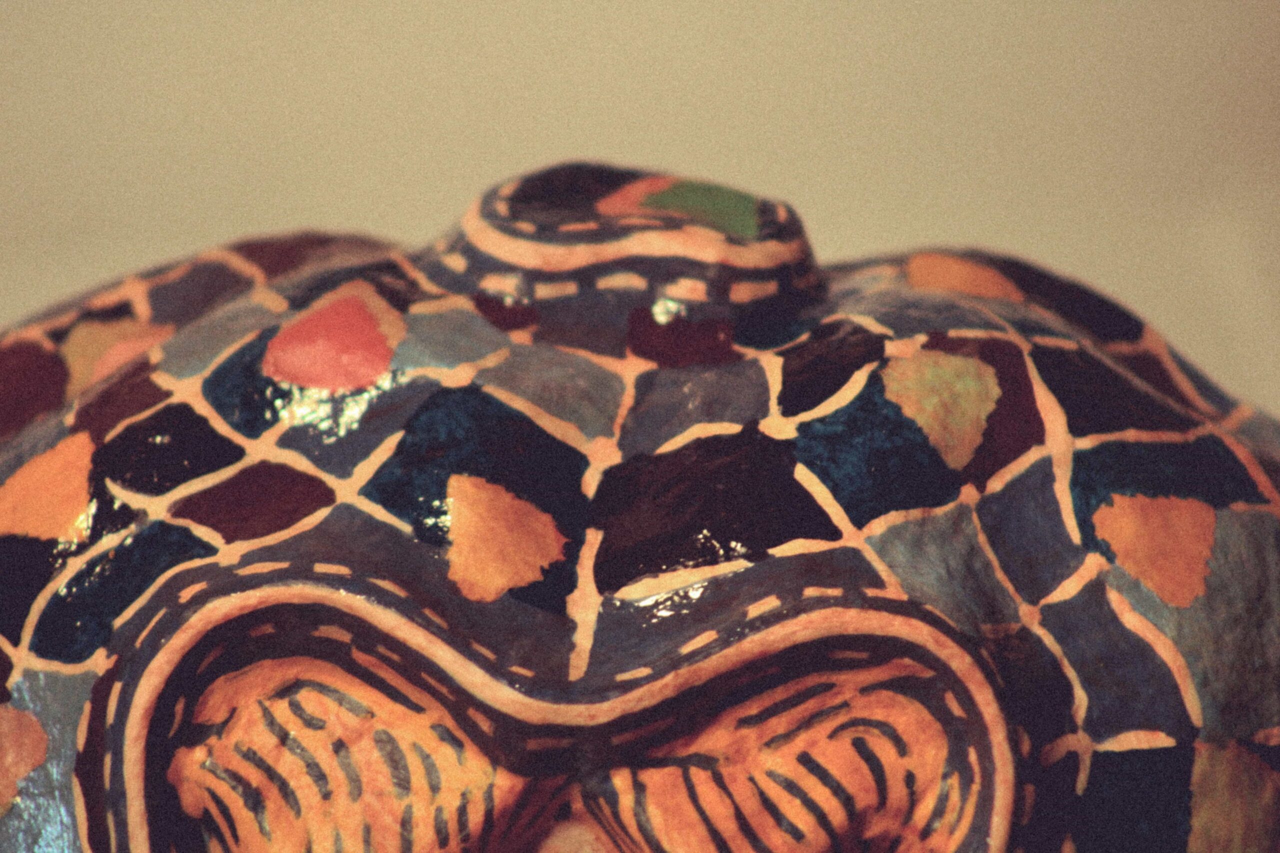 top close-up of a contemporary sculptural mask with multicolored mosaic pattern and glossy surface