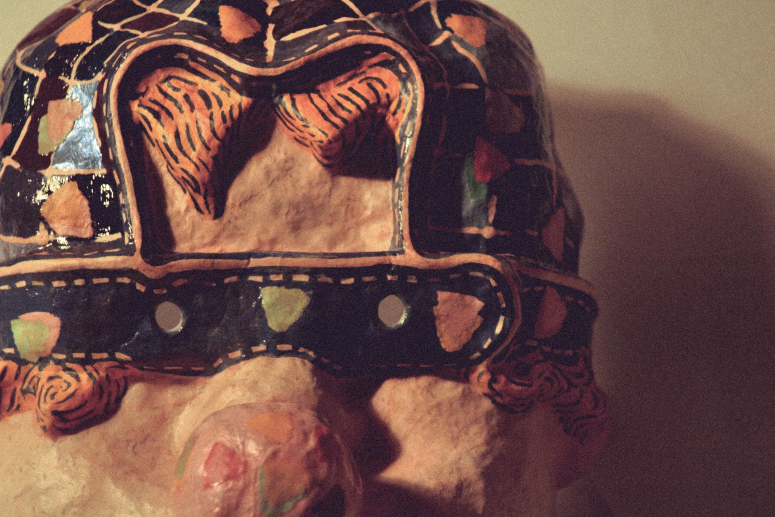 front view of a handmade mask, with painted surface and cut-out eye opening